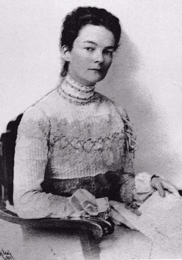 A portrait of a woman with short hair. She is wearing an older style dress
