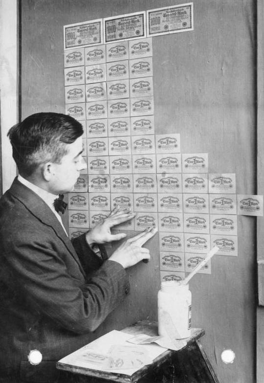 A man pasting old German banknotes on a wall as wallpaper