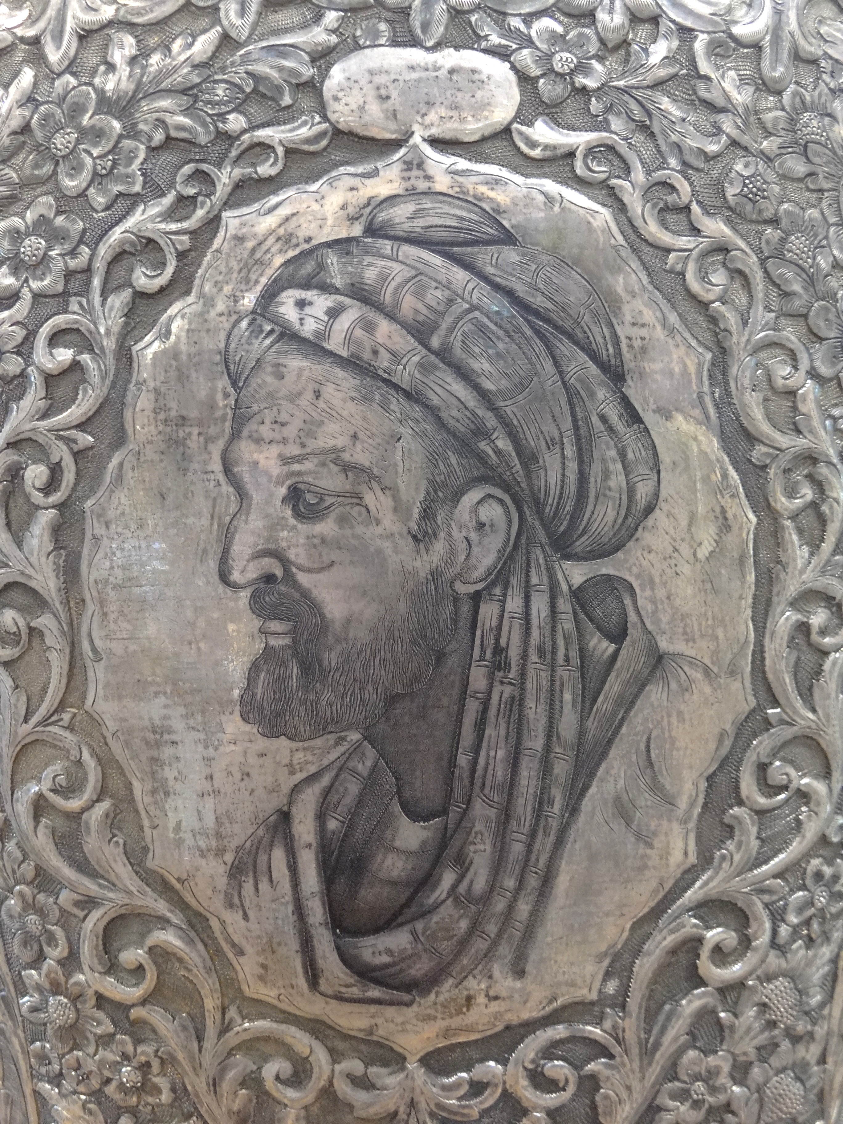 Profile portrait of Ibn Sina wearing a turban etched on a silver vase