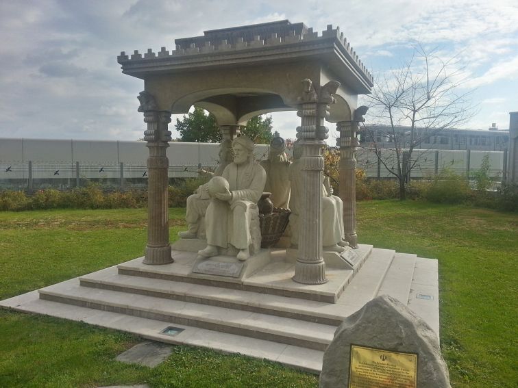 Statues of Islamic scientists under a stone overhang. The stone figures are seated and each holds an object related to their science (book, globe, flask, etc.)